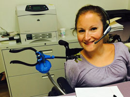 Kim at her work desk with the mouth grabber on a stand.