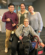 Photo of a team of students, a wheelchair user, and her service dog