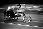 A racer in a high performance wheelchair presses hard along the racing track.